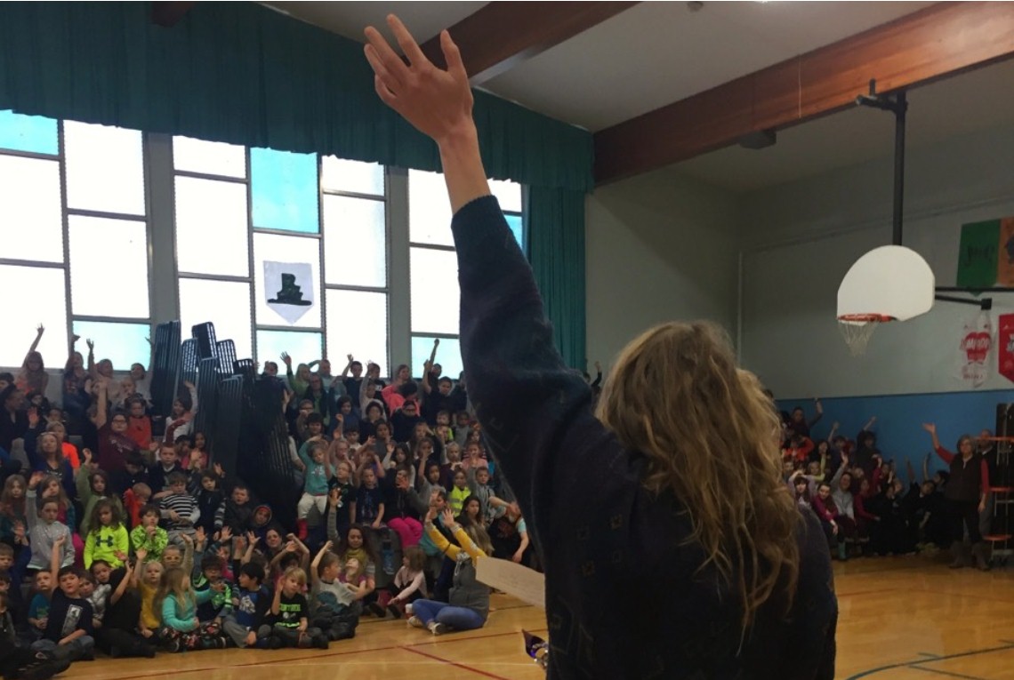 Kate Perkins science presentation to gymnasium of elementary school students